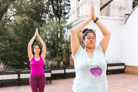 Young hispanic women doing yoga standing raising arms outdoors in Mexico Cityの写真素材