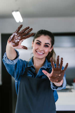 young latin woman with mexican chocolate in hands in process of preparing delicious sweets chocolates at kitchen in Mexico Latin Americaの写真素材