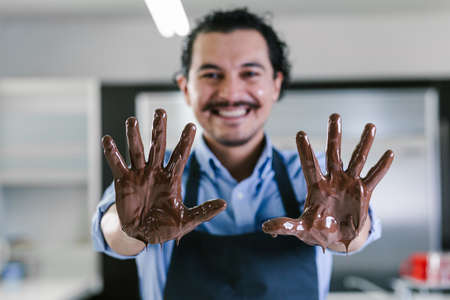 young latin man with mexican chocolate in hands in process of preparing delicious sweets chocolates at kitchen in Mexico Latin Americaの写真素材