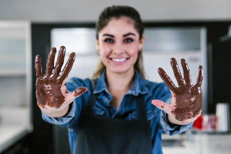 young latin woman with mexican chocolate in hands in process of preparing delicious sweets chocolates at kitchen in Mexico Latin Americaの写真素材