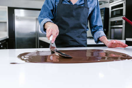 hand of latin woman pastry chef wearing black uniform in process of preparing delicious sweets chocolates at kitchen in Mexico Latin Americaの写真素材