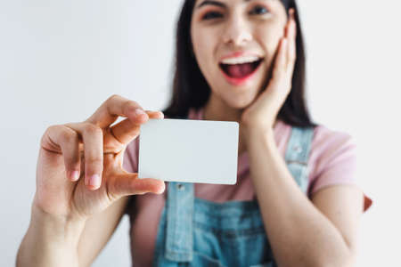 Young latin woman holding a blank empty card isolated on white background in Latin Americaの写真素材