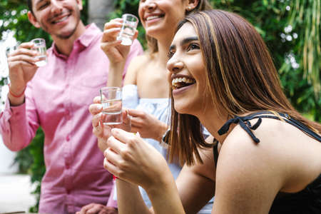 tequila shot, Group of Young latin Friends Meeting For tequila shot or mezcal drinks making A Toast In Restaurant terrace in Mexico Latin Americaの写真素材