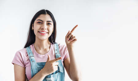 young latin woman pointing at copy space looks in camera in Latin Americaの写真素材