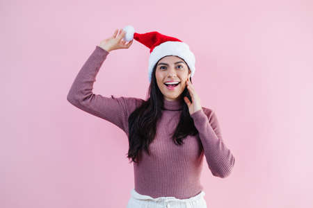 Portrait of young latin woman with copy space in a christmas concept on pink backgroundの写真素材