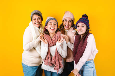 Winter portrait of happy latin family three generations of hispanic women on yellow background in Mexico Latin Americaの写真素材