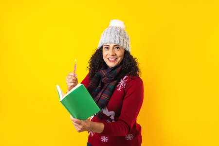 latin woman holding christmas candles and singing carols on yellow background in Mexico Latin Americaの写真素材