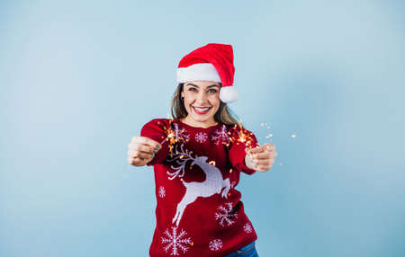Adult hispanic woman holding christmas sparkling lights for mexican posada in christmas on yelllow background in Mexico Latin Americaの写真素材