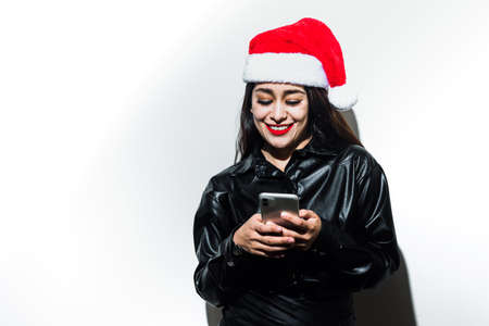 Portrait of latin woman with Santa's hat for christmas calling and texting mobil phone on white backgroundの写真素材