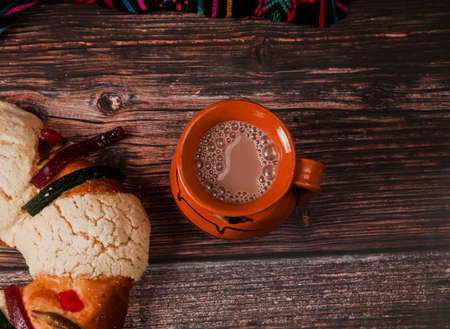 Rosca de reyes or Epiphany cake and clay mug of mexican hot chocolate on a wooden table in Mexico Latin Americaの写真素材