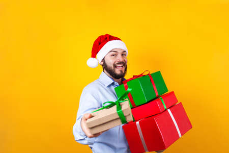 Portrait of young Latin man holding Christmas gift box on a yellow background in Mexico Latin...