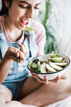 young latin woman eating vegetable or salad bowl, healthy food at home in Mexico Latin Americaの写真素材