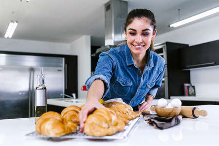 young Latin woman baking croissant ingredients in kitchen in Mexico Latin Americaの写真素材