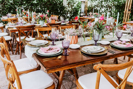 terrace with tables setup with flowers and plates on table decorated for Wedding Reception in Latin...