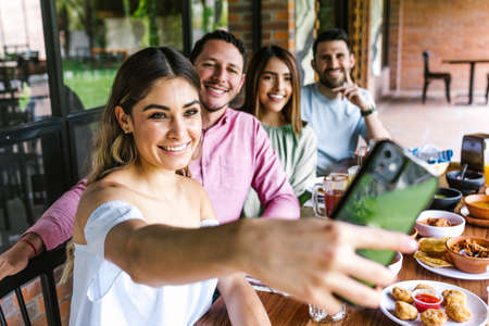 Group of latin friends taking a photo selfie and eating mexican food in the restaurant terrace in Mexico Latin Americaの写真素材