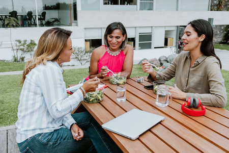 transgender latin business woman middle age and colleagues eating salad at the office terrace in Mexico Latin Americaの写真素材