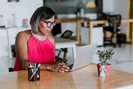 transgender latin woman working with computer at the office in Mexico Latin America