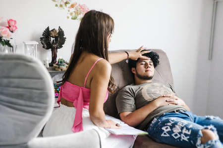 Young hispanic female in a regression session with young man lying on the couch in holistic therapy...