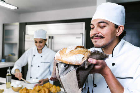 young Latin man baker and baking bread on oven at kitchen in Mexico Latin America