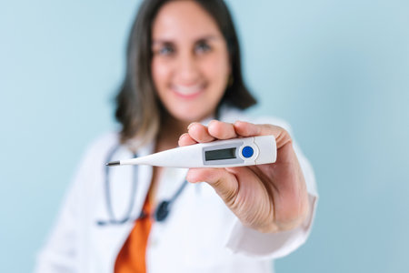 Latin woman doctor Close up holding thermometer isolated over blue color background in Latin Americaの写真素材