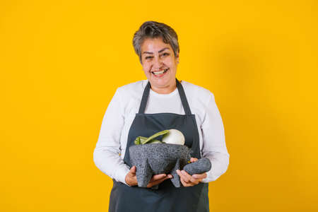 Portrait of hispanic woman middle aged cooking and holding mexican mortar with sauce ingredients in Mexico Latin Americaの写真素材