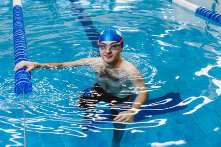 hispanic young man swimmer athlete wearing cap and goggles in a swimming training at the Pool in...