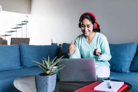 Young hispanic woman working or studying in a video call online with laptop at home in a home office...