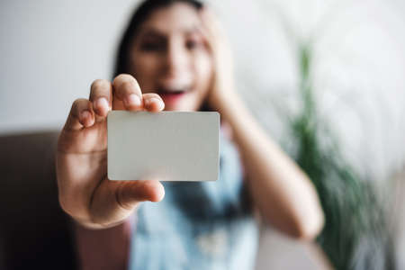 young latin woman holding a blank card with copy space at home in Mexico Latin Americaの写真素材