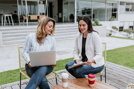 Two latin business woman middle age, talking and advising each other at the office in Mexico Latin...