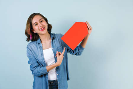 Portrait of hispanic girl smiling looking at camera and pointing finger to copy space blank card on...