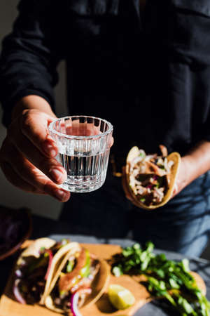 Mexican woman hands holding tacos and mezcal shot traditional food in Mexico cityの写真素材