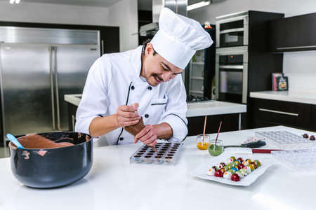 latin man pastry chef wearing uniform in process of preparing delicious sweets chocolates at kitchen in Mexico Latin Americaの写真素材