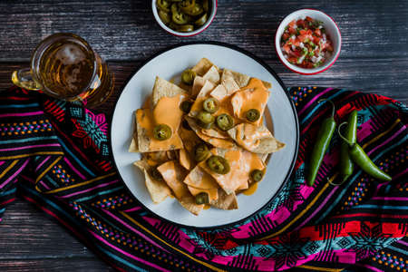 Mexican nachos with guacamole and salsa on a wooden table