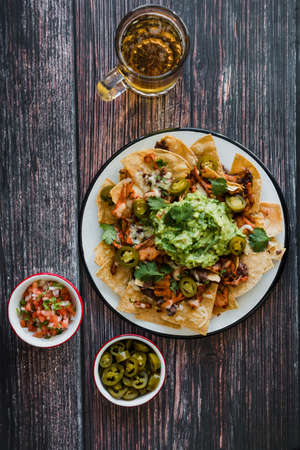 Mexican nachos with guacamole and salsa on wooden backgroundの写真素材