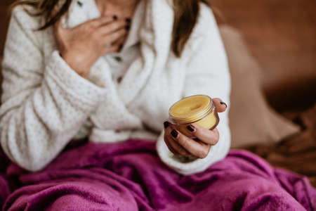 Woman in a bathrobe with a jar of cream in her hands.の写真素材
