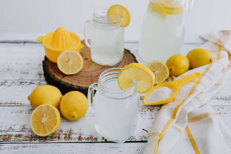 Lemonade in a glass jar with lemon slices on a white wooden backgroundの写真素材
