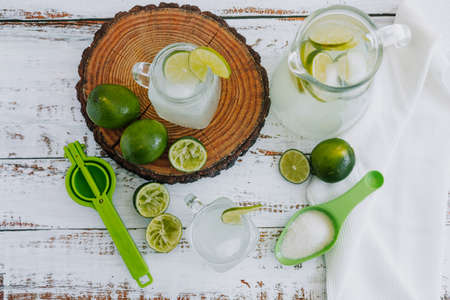 Lemonade with lime and ice in a glass on a white wooden background.の写真素材
