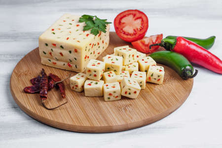 Tofu cheese with chili pepper and tomato on wooden cutting board