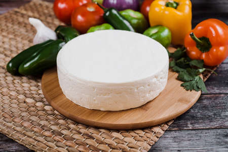 Fresh cheese with vegetables on a wooden background. Close-up.