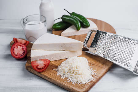 Fresh feta cheese with grater and ingredients on white wooden backgroundの写真素材