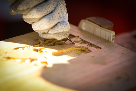 Carpenter carving wood with a chisel at work