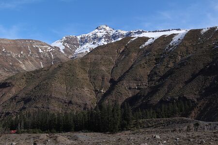 A valley in the Andes mountain range in Chile, between snowy rocky mountains