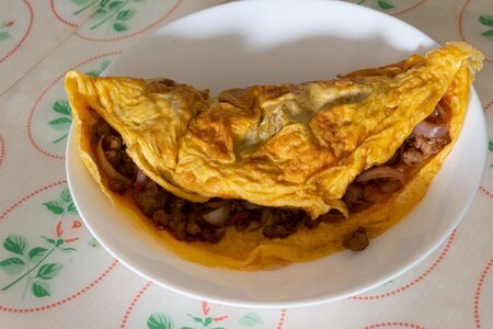 Omelette, a delicious homemade omelet with meat and onion served on a white plate on the table.の写真素材