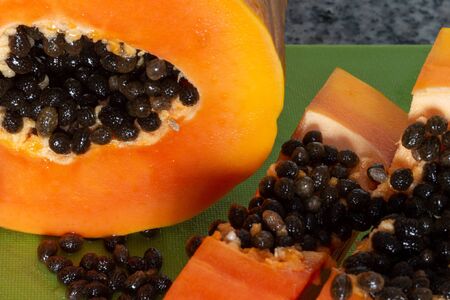 Delicious sweet orange papaya fruit cut on pieces on a green cutting boardの写真素材