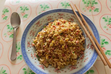 A plate of fried rice with ham and mushroom served o na table in a restaurantの写真素材