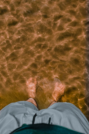 Close-up of a man's feet on the sand in the seaの写真素材