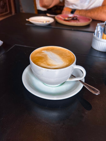 Hot latte art coffee in white cup on wooden table, Thailand.の写真素材