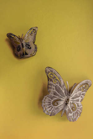 metal butterflies hanging on a yellow wall - yellow backgroundの写真素材