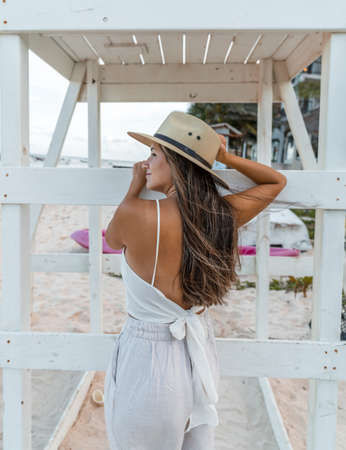 young model with hat posing from behind leaning on a wooden structure looking at the seaの写真素材