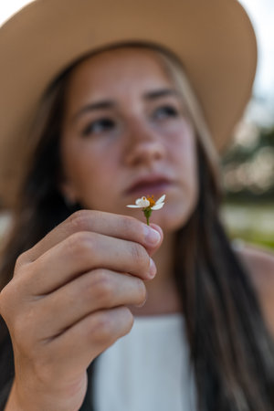 young model with hat on the beach holding a flowerの写真素材